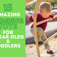 A small toddler boy in a red sweater and brown pants concentrates as he climbs up an outdoor metal ladder. Text overlay says 15 amazing climbing toys for 1 year olds and toddlers Thegiftygirl.com